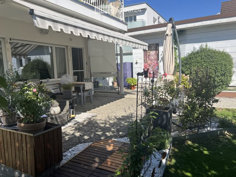 Well-maintained garden with patio seating, potted plants, and a covered outdoor dining area.