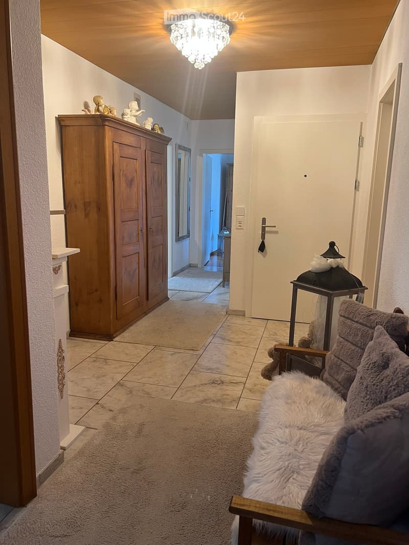 Hallway with a small seating area featuring a plush sofa with pillows, a lantern, and a wooden cabinet adorned with decorative statues.
