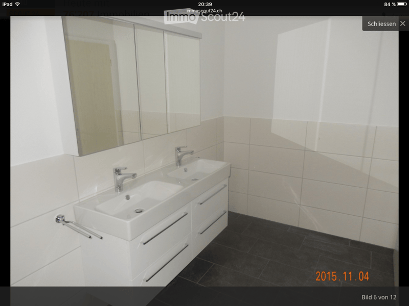 Modern bathroom with white tiled walls, black tiled floor, double sink vanity with mirrored cabinet, and sleek chrome faucets.