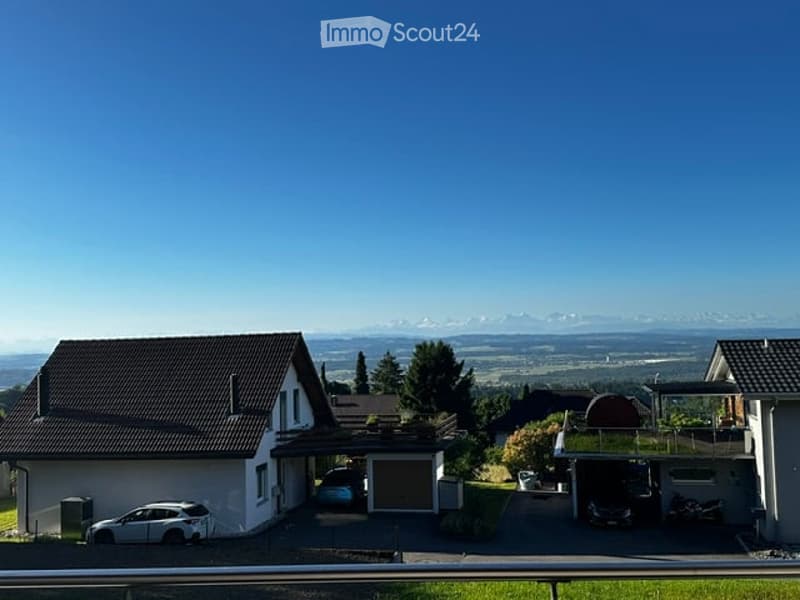 View of a residential area with houses, parked cars, and a scenic mountain backdrop.