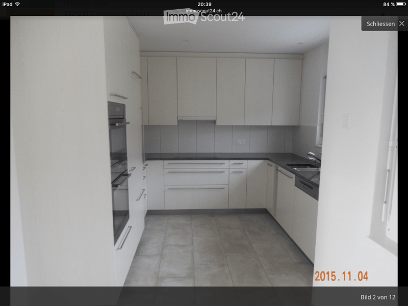 Modern kitchen with white cabinets, stainless steel sink, and built-in oven. The space features tiled flooring and ample storage.