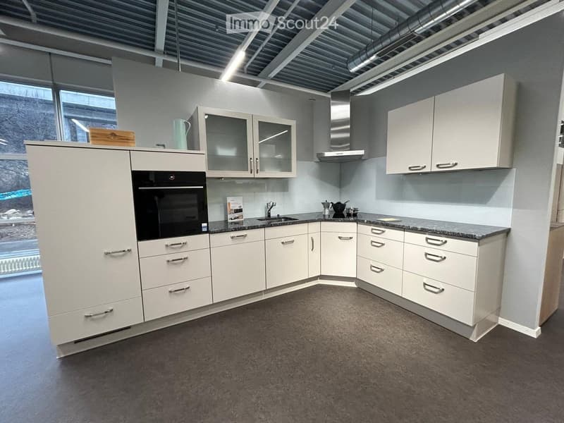 Modern kitchen with white cabinets, stainless steel appliances, granite countertop, and large windows.