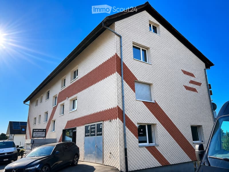 Two-story building with white and red patterned facade, multiple windows, and a garage entrance.
