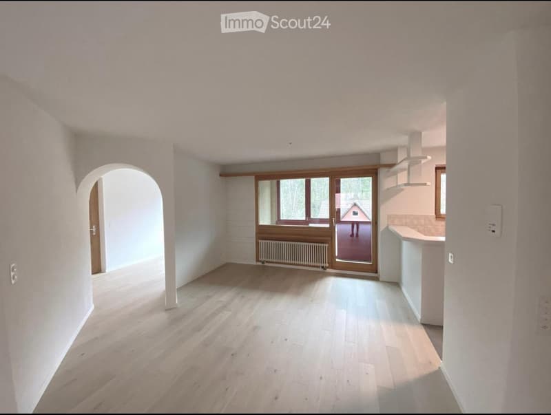 Empty room with light wooden flooring, white walls, and large windows. No furniture or equipment present.