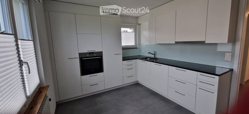 Modern kitchen with white cabinets, black countertops, and stainless steel appliances including an oven and sink.