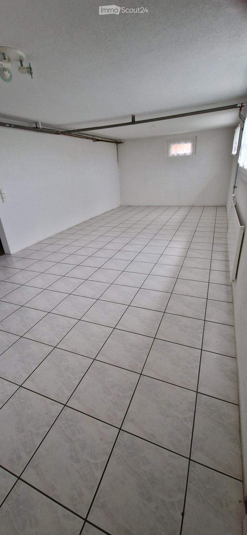 Empty room with tiled floor and white walls, featuring a small window and electrical outlet.