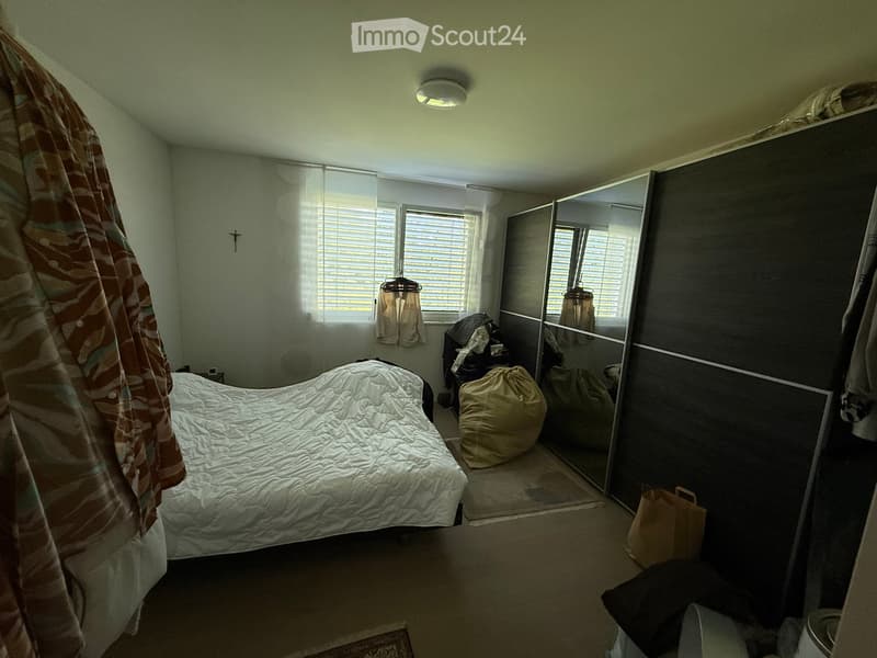 Bedroom with a bed, wardrobe, mirror, chair, and handbag visible.