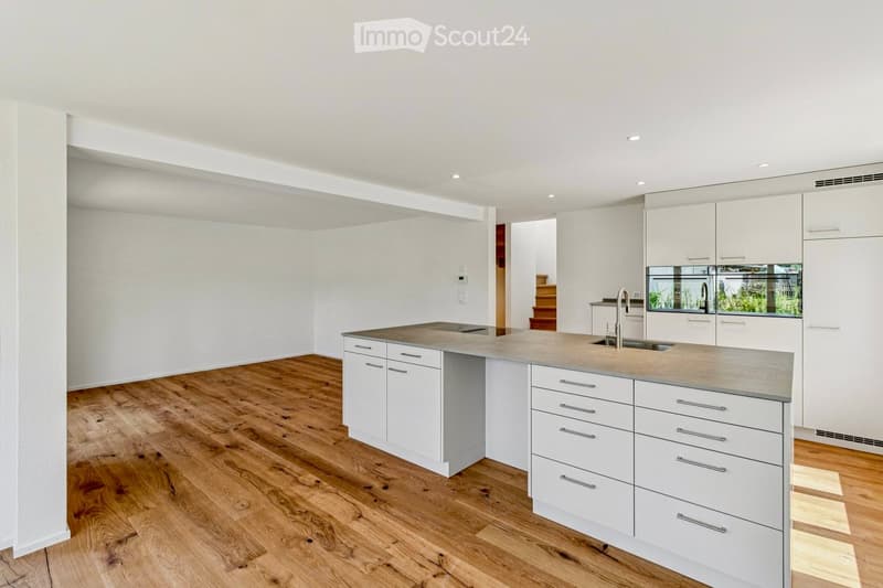 Modern kitchen with white cabinets, a central island, and a wooden floor. Features a sink with a modern faucet and ample storage space.