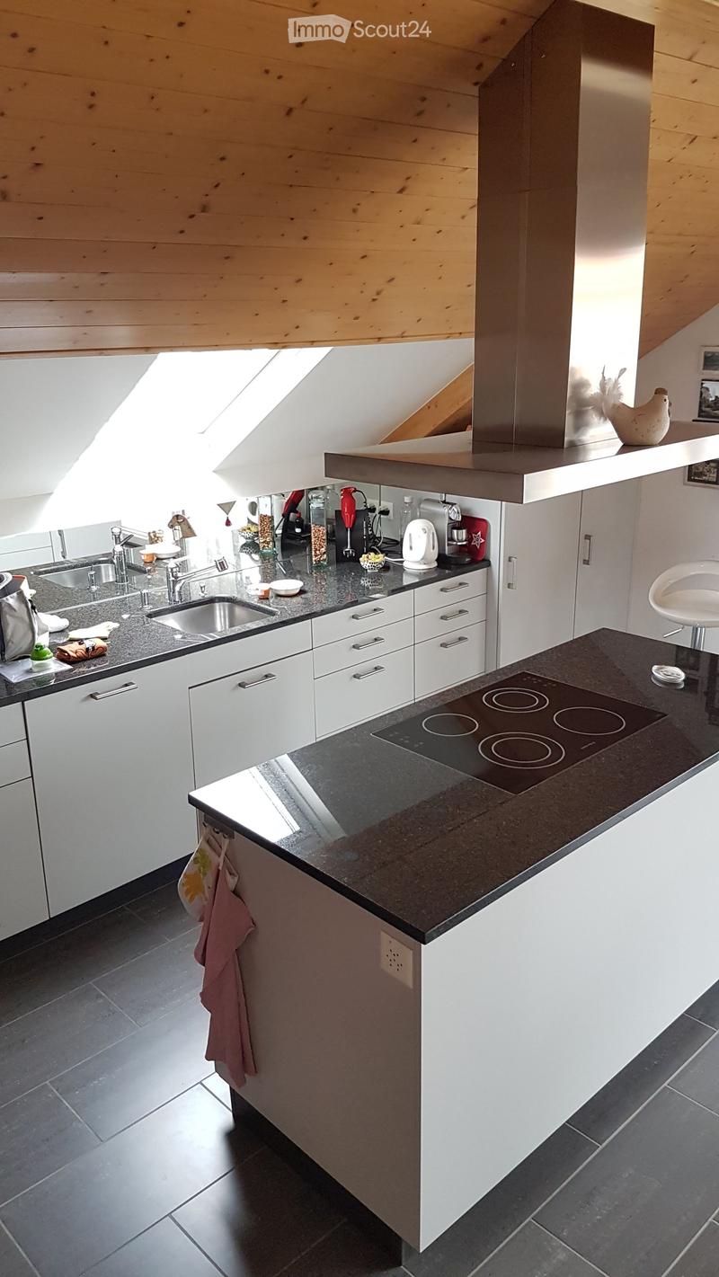 Modern kitchen with white cabinets, dark countertops, stainless steel appliances, and a central island with an induction cooktop. Features include a sink, faucet, stove, and various appliances.
