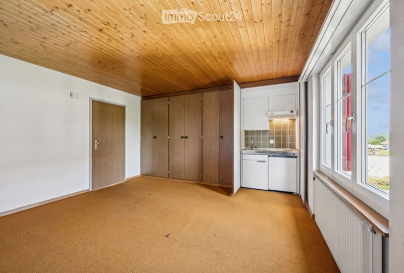 Bright kitchen with wooden cabinets, white appliances, and large windows offering a view.