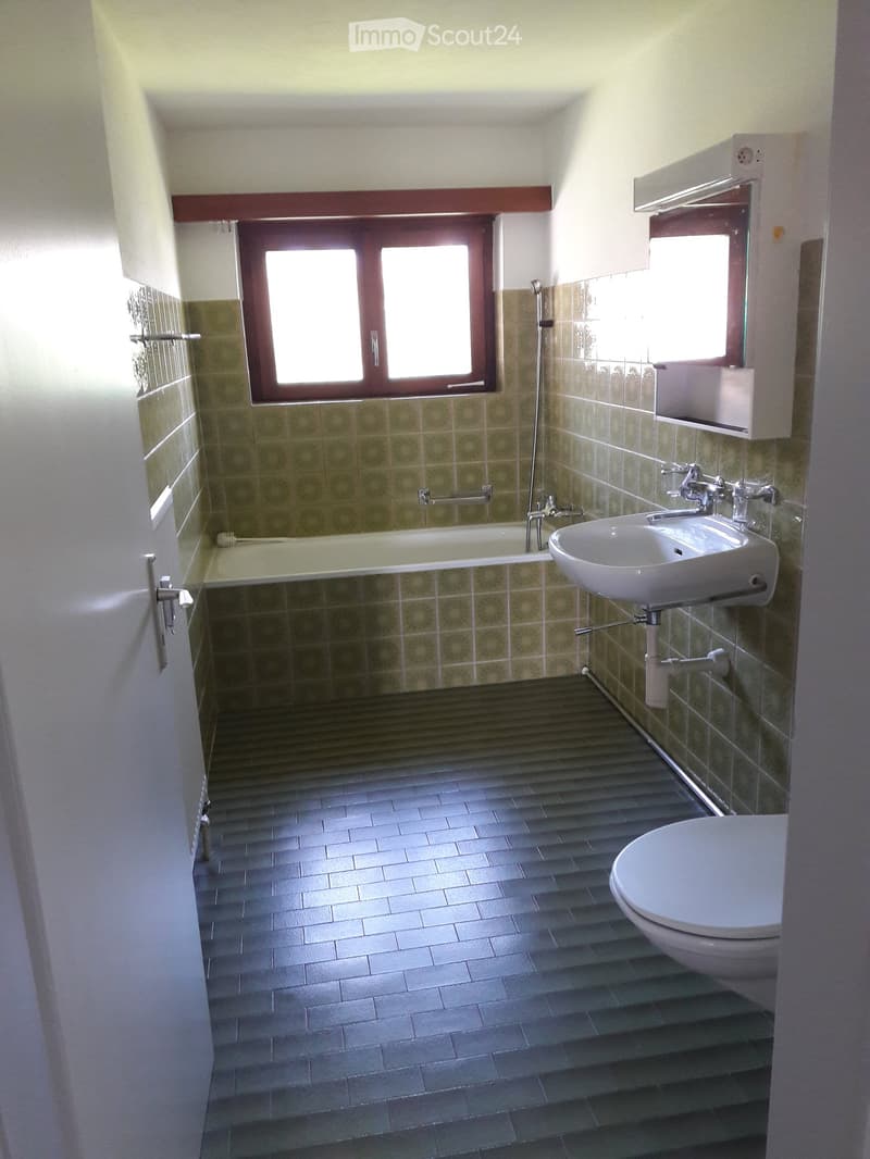 Bathroom with a bathtub, toilet, sink, tiled floor, and a window