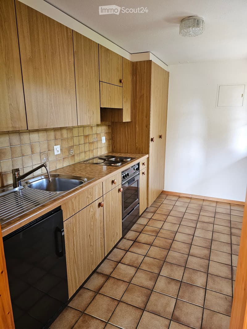 Modern kitchen with light wooden cabinets, tiled backsplash, and stainless steel appliances including a sink, oven, and dishwasher.