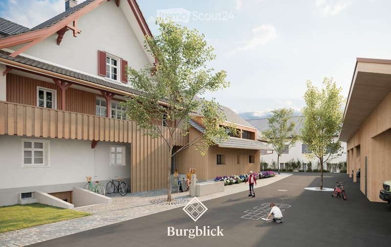 A modern residential complex with a raised ground floor, featuring a balcony, bicycles, and a landscaped garden area with trees and flowers.