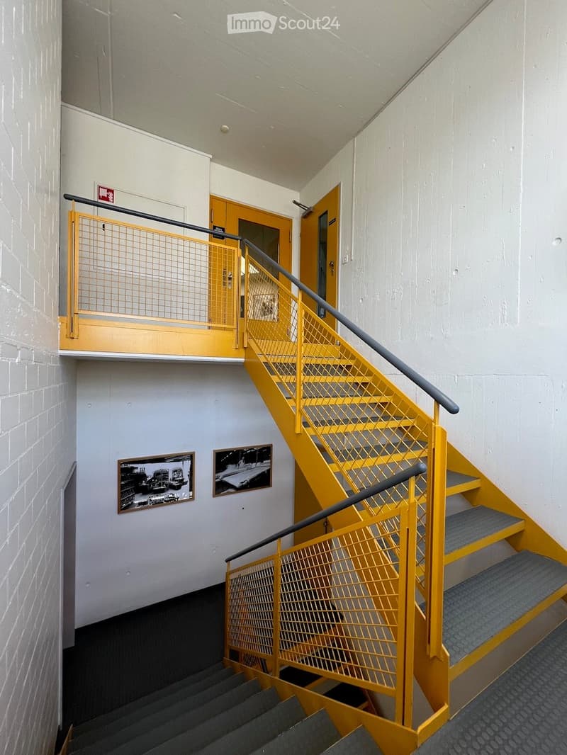 yellow staircase with gray handrails, two picture frames on the wall