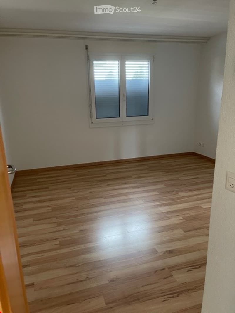 Empty room with wooden flooring and a single window with blinds. No furniture or equipment present.