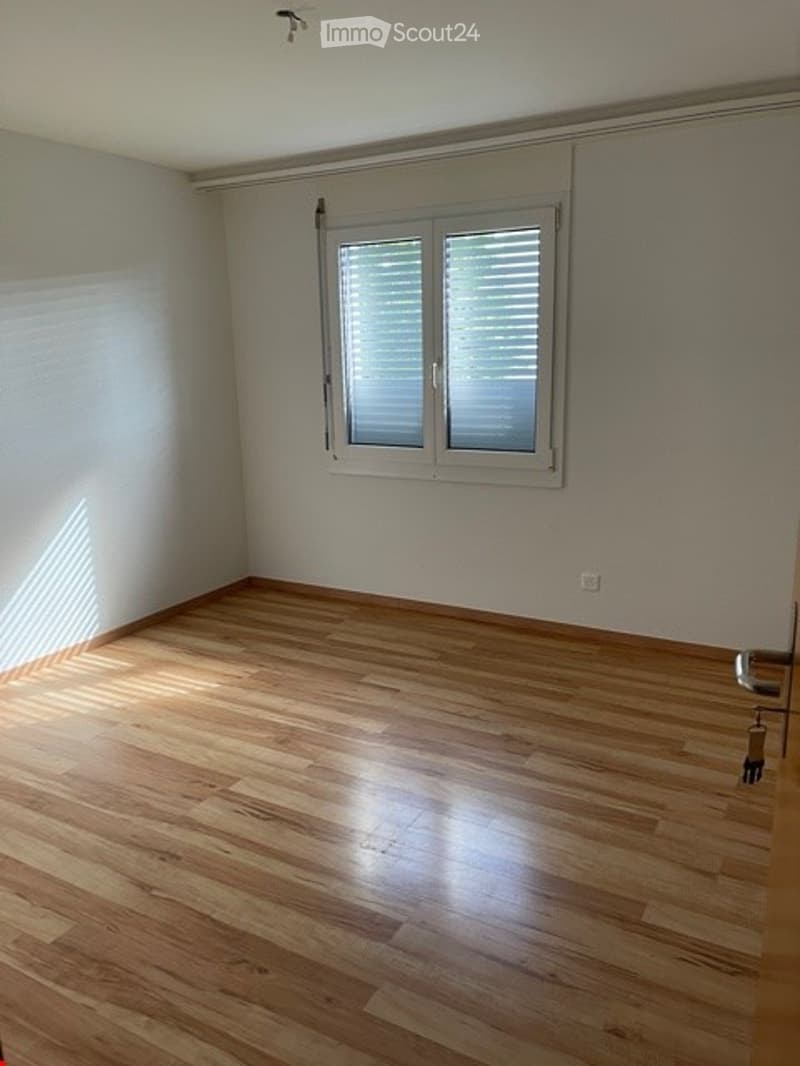 Empty room with wooden flooring, white walls, and a window with blinds. No furniture or equipment present.