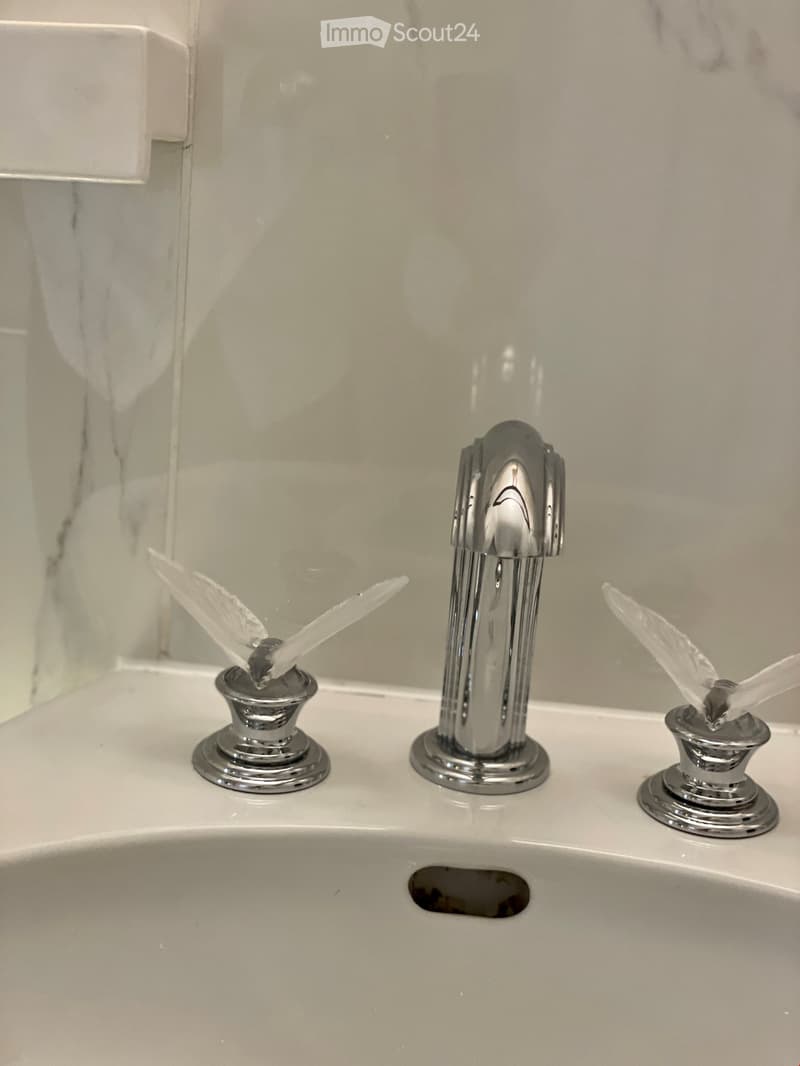 Modern bathroom sink with a chrome faucet and toothbrush holders with toothbrushes on either side.