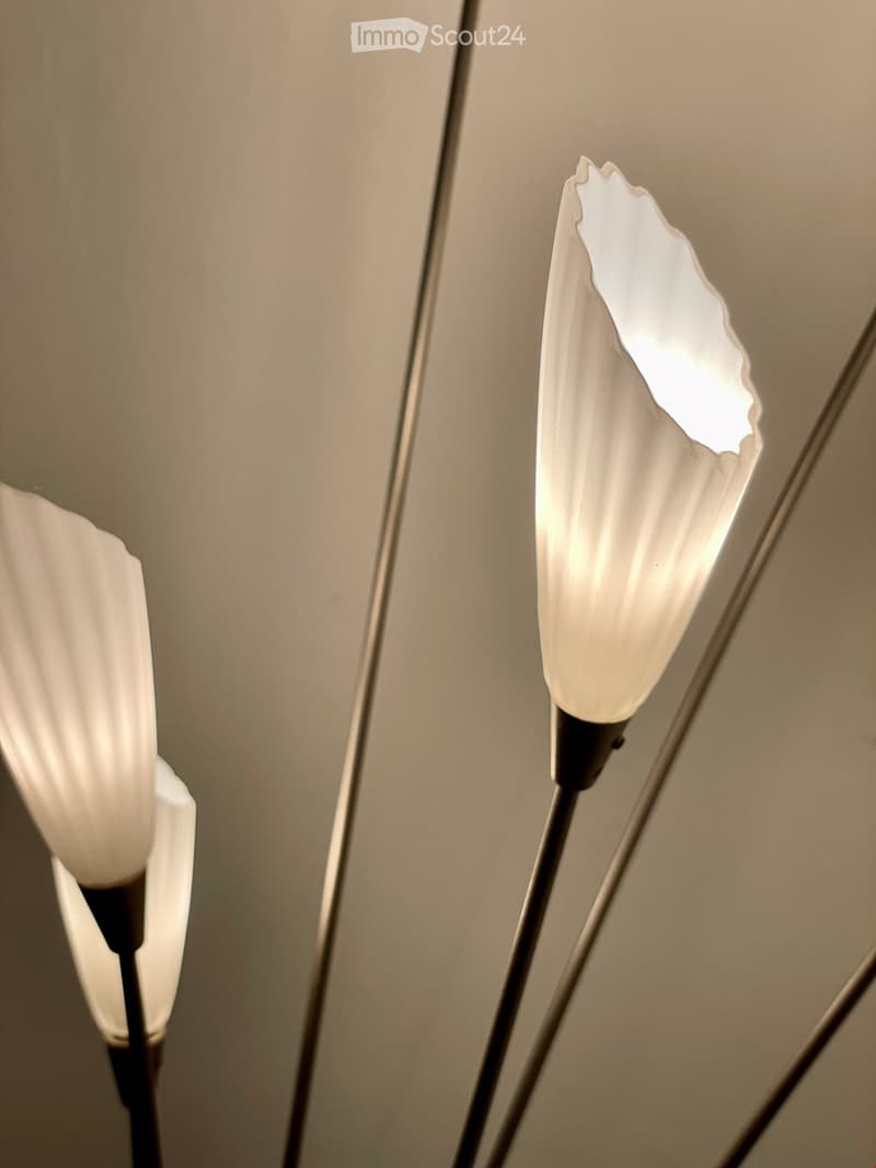 Two modern floor lamps with white, teardrop-shaped shades mounted on a wall, emitting soft light.
