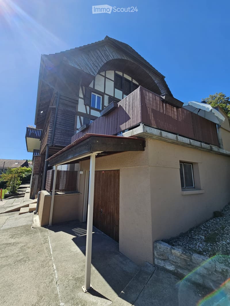 Two-story house with wooden exterior, multiple balconies, and a covered entrance area.