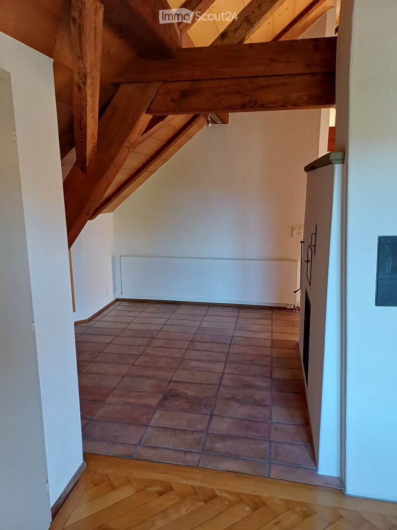Hallway with wooden staircase, tiled floor, white walls, radiator, and visible electrical outlets.