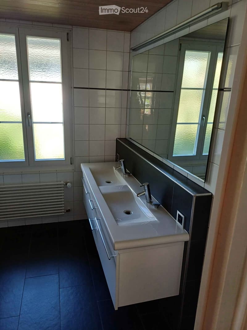 Modern bathroom with a double sink, chrome faucets, large mirror, and radiator.