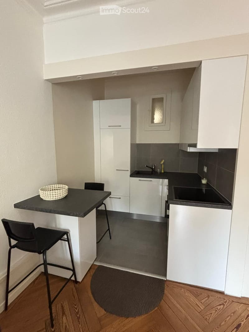 small kitchen, white cabinets, granite counter top, black sink, wooden floor, bar area with chairs