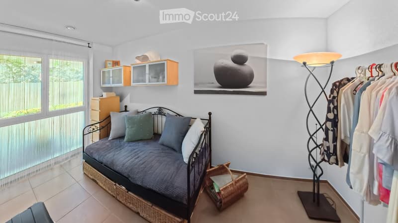 Cozy bedroom with a daybed, pillows, a wicker basket, a modern floor lamp, a wardrobe, and a cabinet with glass doors.