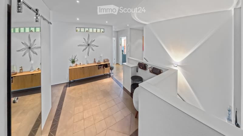Modern hallway with white walls, wooden flooring, built-in storage units, decorative wall art, and small seating area with black stools.