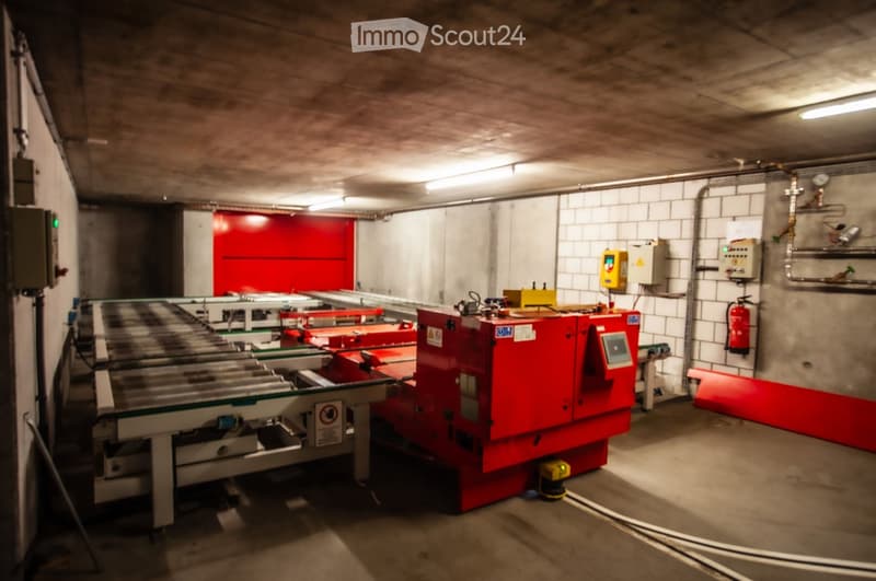 Underground parking area with industrial machinery, control panels, and a fire extinguisher mounted on the wall.
