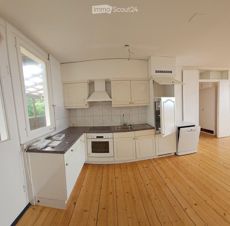 Modern kitchen with white cabinets, wooden flooring, and stainless steel appliances including an oven, refrigerator, and dishwasher.