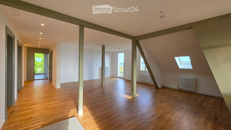 Empty attic space with wooden flooring, white walls, exposed wooden beams, and skylight windows. No furniture or equipment present.