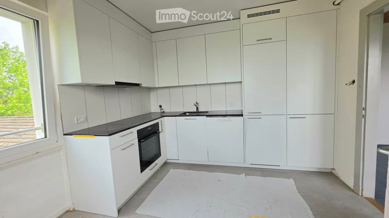 Modern kitchen with white cabinets, black countertop, and stainless steel appliances.