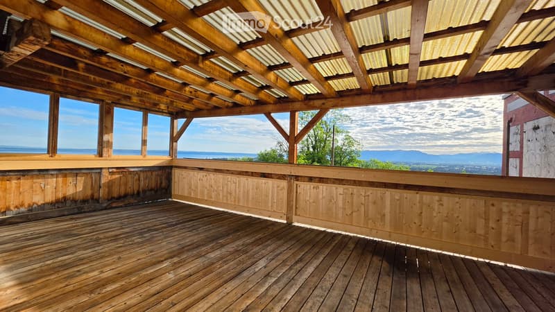 Wooden deck with open wooden beams and railings, offering a scenic view of the ocean and distant mountains.
