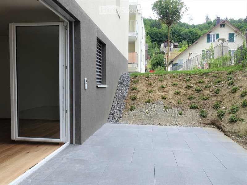 an exterior patio entrance, grey tiles, concrete wall, and a door with a glass panel