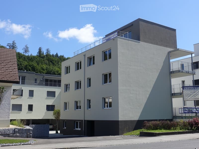3 story building, white exterior, balconies on upper floors, entrance with parking lot