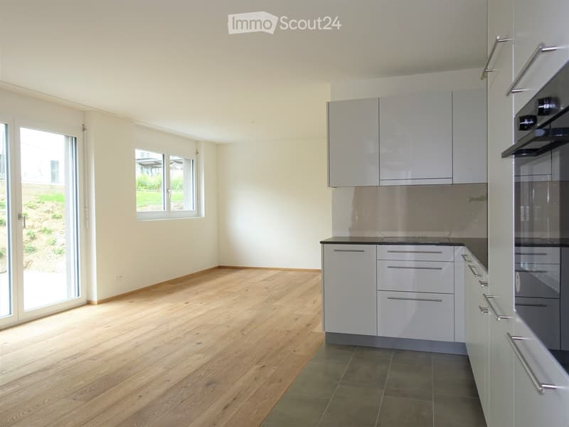 white kitchen cabinets, stainless steel appliances, sliding door to balcony, hardwood floors, large windows