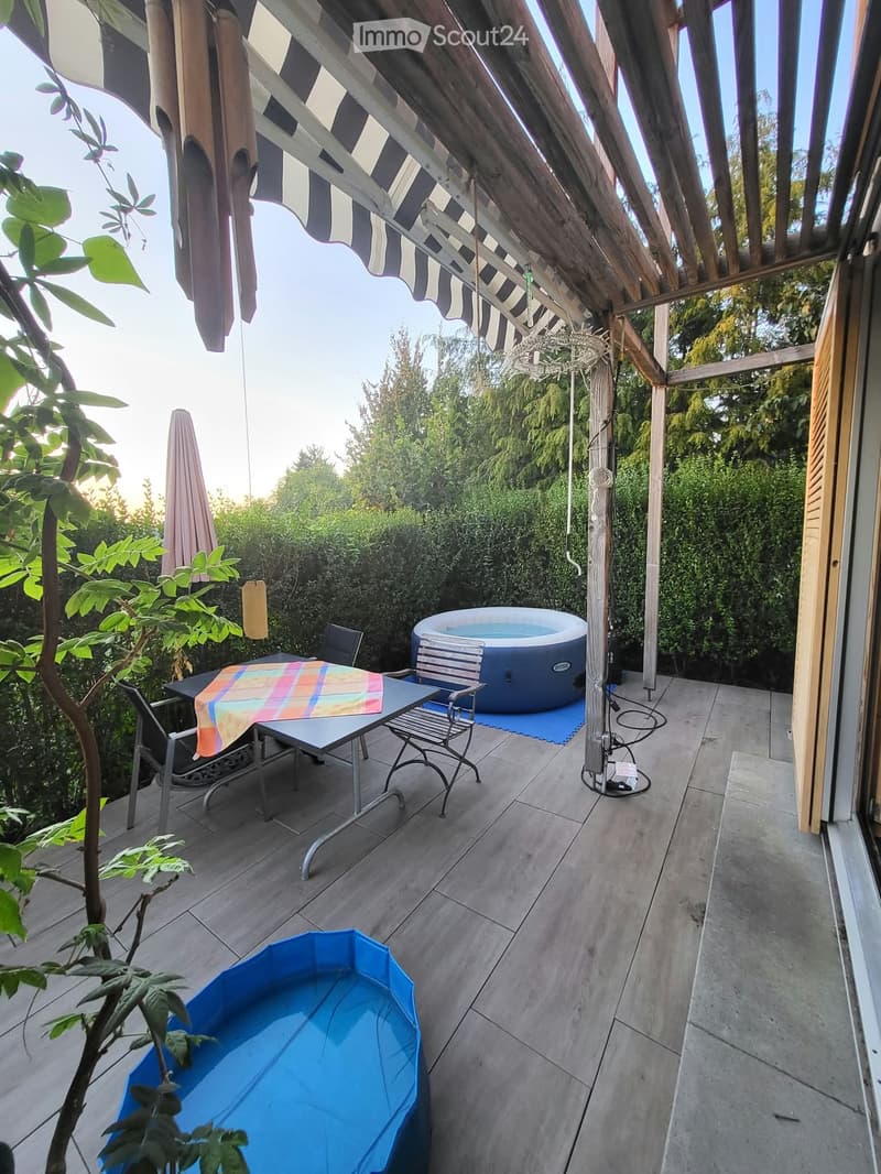 Outdoor patio with a small swimming pool, a table with chairs, and an umbrella.