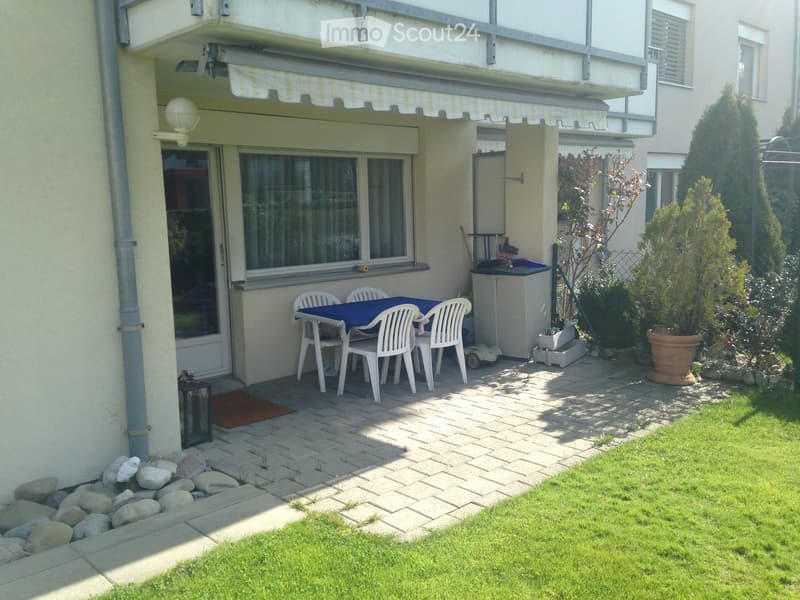 Garden area with a patio, table, chairs, and surrounding greenery.