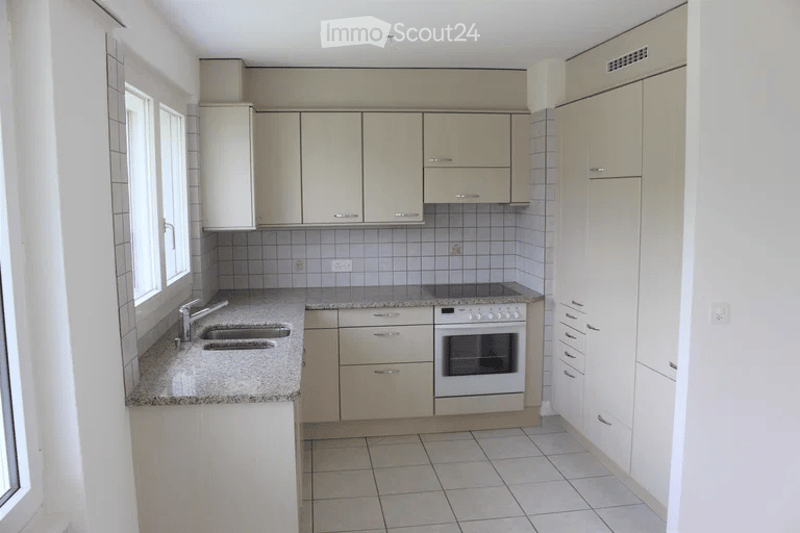 Modern kitchen with light-colored cabinets, granite countertops, and a built-in oven. Features a double sink and ample storage space.