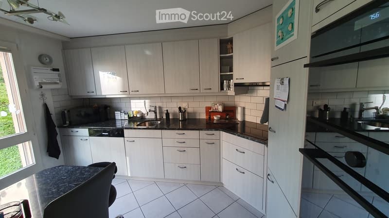 Modern kitchen with white cabinets, black marble countertop, stainless steel sink and faucet, and an oven