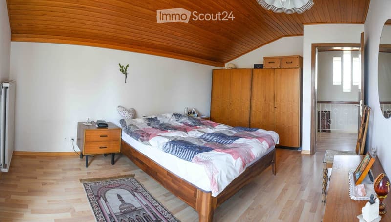 Cozy bedroom with wooden bed, nightstand, wardrobe, and a small table near the door.