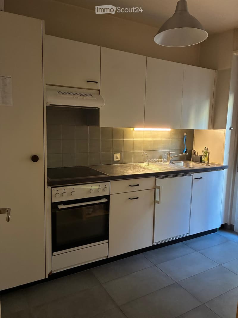Modern kitchen with white cabinets, stainless steel sink, oven, and built-in lighting above the counter.