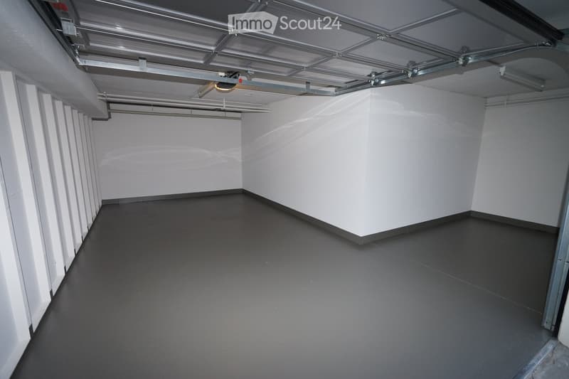Empty room with white walls, dark grey floor, and exposed metal ceiling structure. No furniture or equipment present.