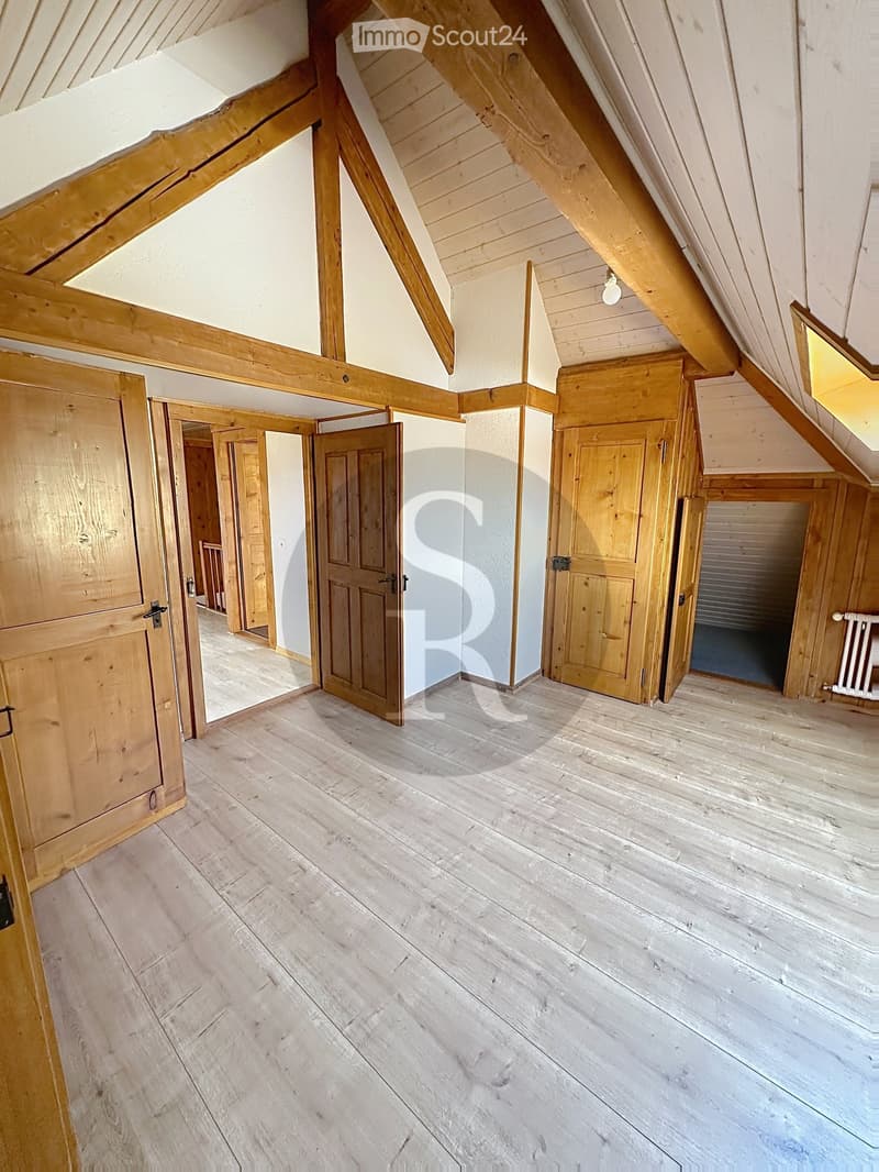 Empty attic space with wooden beams, wooden doors, and wooden flooring.