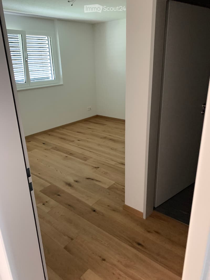 Empty room with light wooden flooring, white walls, and a window with blinds. No furniture or equipment is present.