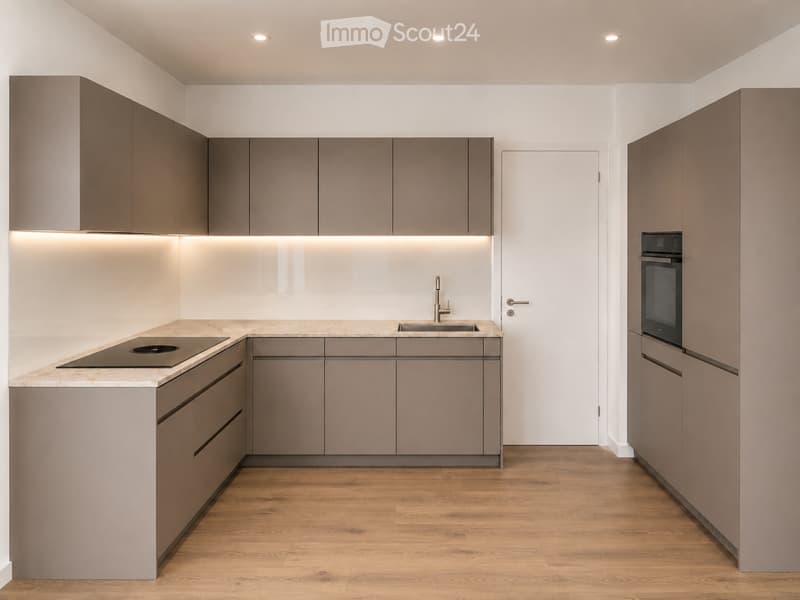 Modern kitchen with grey cabinets, marble countertop, built-in oven, induction cooktop, and sink with faucet.