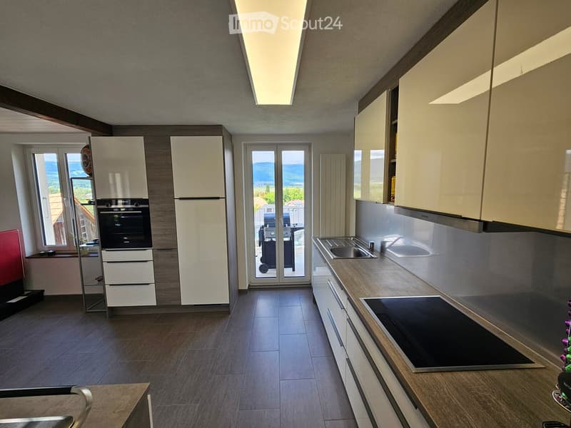 Modern kitchen with white cabinets, stainless steel appliances, and a large window overlooking a scenic view.