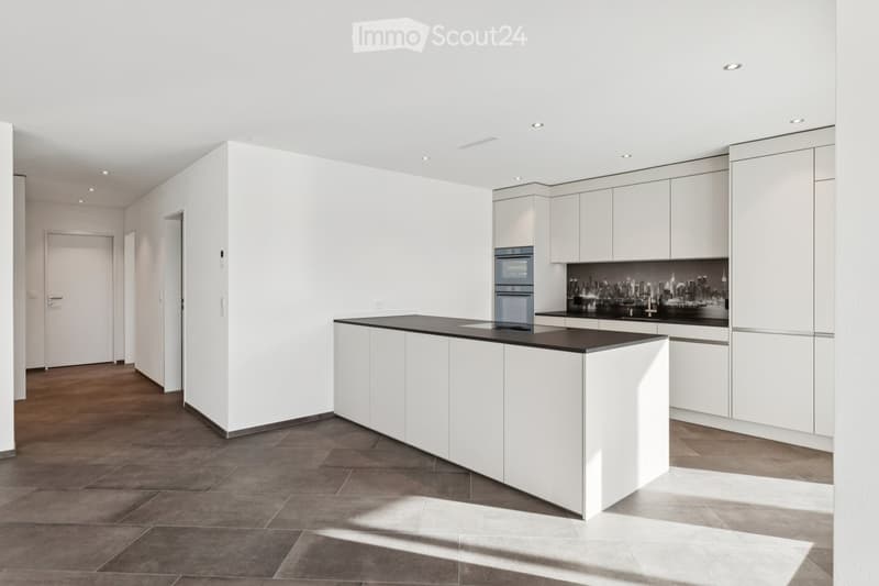 Modern kitchen with island counter, tiled flooring, white cabinetry, black countertops, integrated appliances, large windows