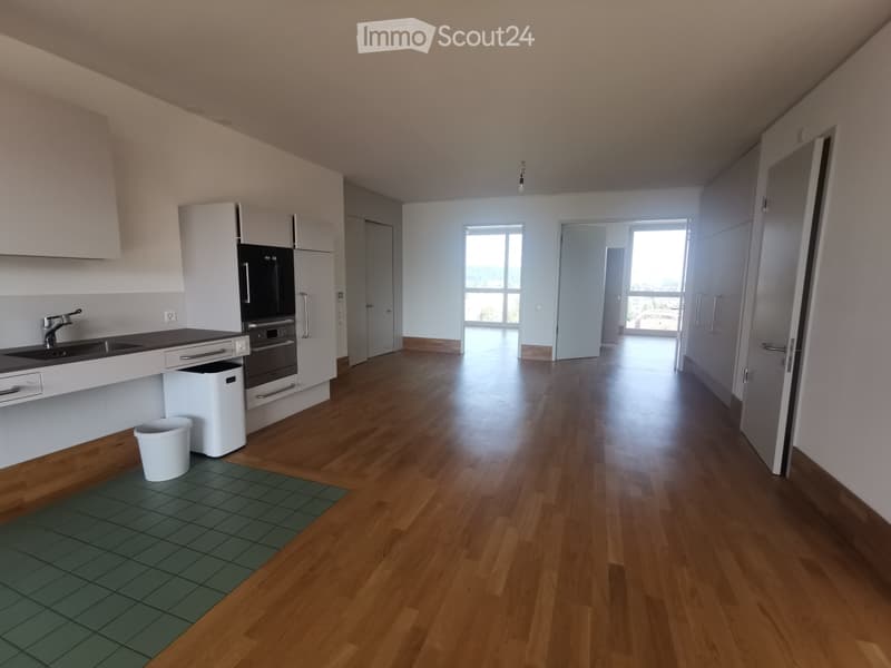Empty room with wooden flooring, white walls, and large windows. No furniture or equipment present.