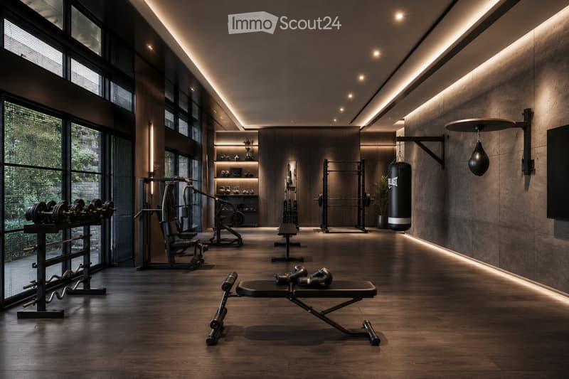 Modern, well-lit gym room with wooden flooring, large windows, and various fitness equipment including a bench, dumbbells, weight machine, and a punching bag.